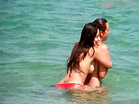 Two bare titted girls enjoying the warm sea in nothing but red bikini panties!