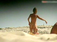 The nudist woman is all naked at the nudism beach demonstrating her slim body, small tits and bushy pussy!